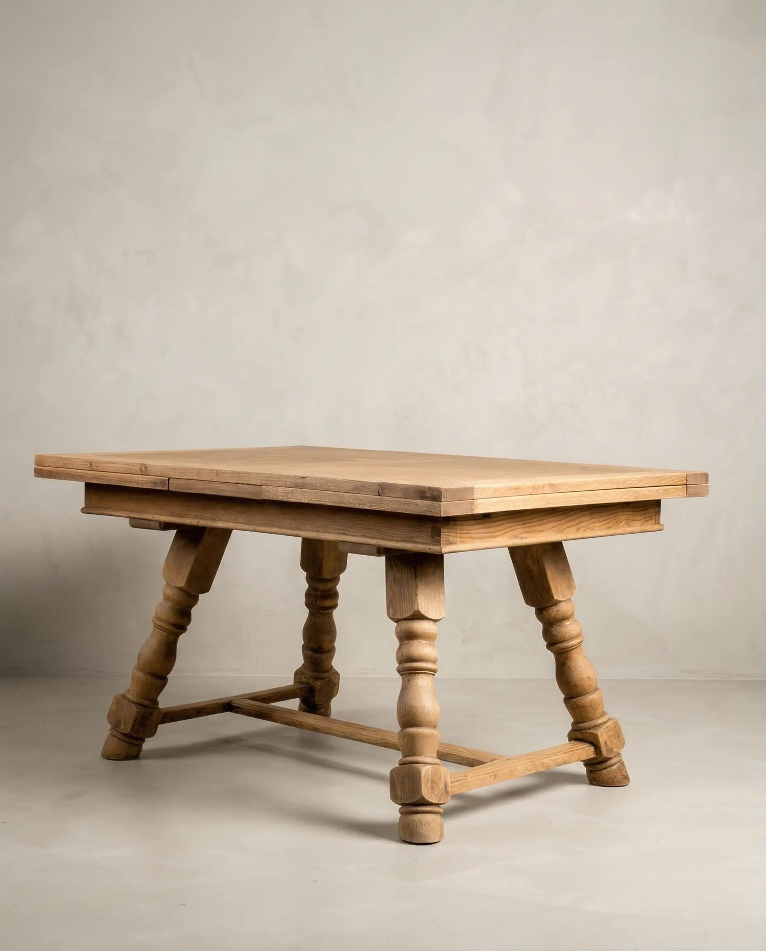 Mesa de comedor rústica cerrada mostrando las potentes patas torneadas y el acabado en madera clara.