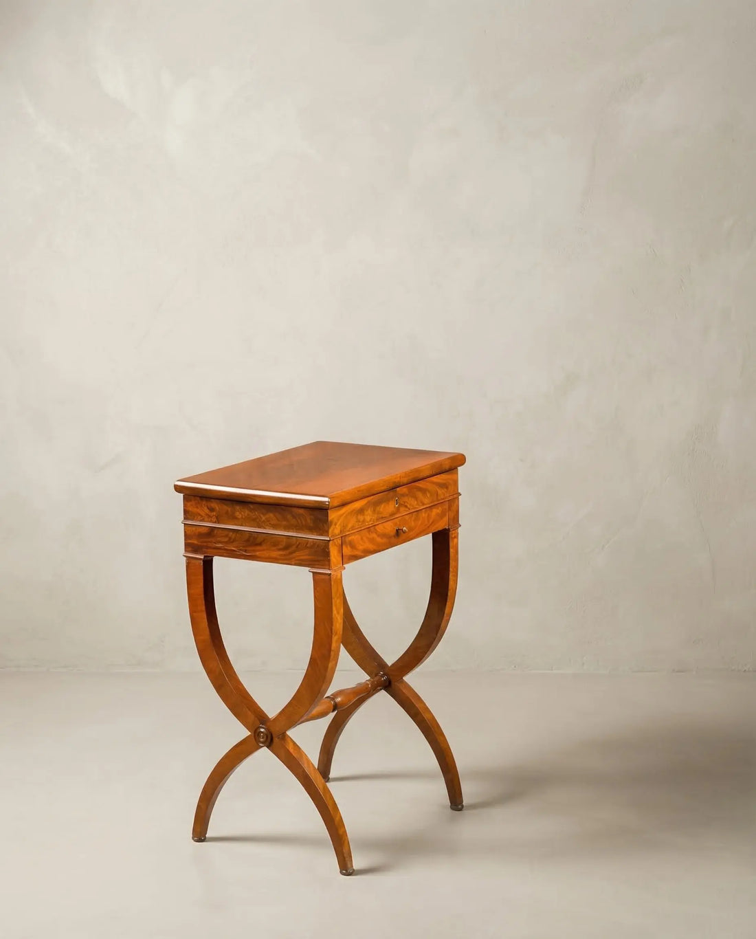Mesa auxiliar vintage de madera de caoba con patas curvas cruzadas en forma de X.