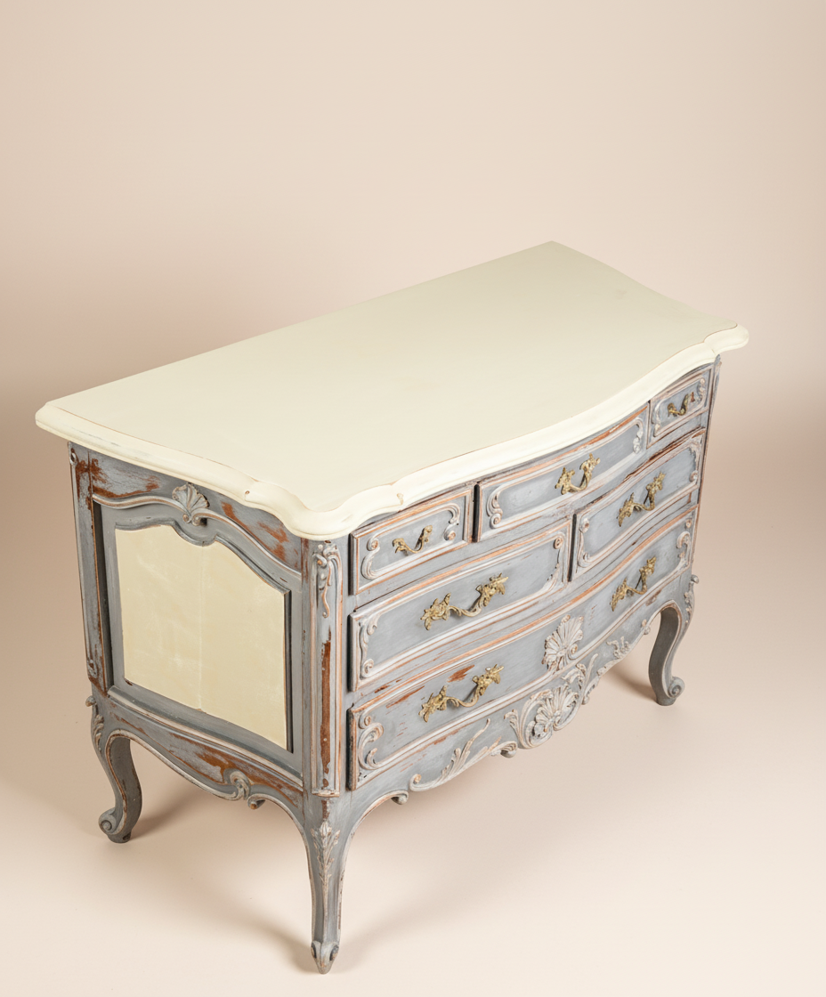 Vista superior en ángulo de la cómoda provincial francesa en gris y crema, destacando su forma serpentina.