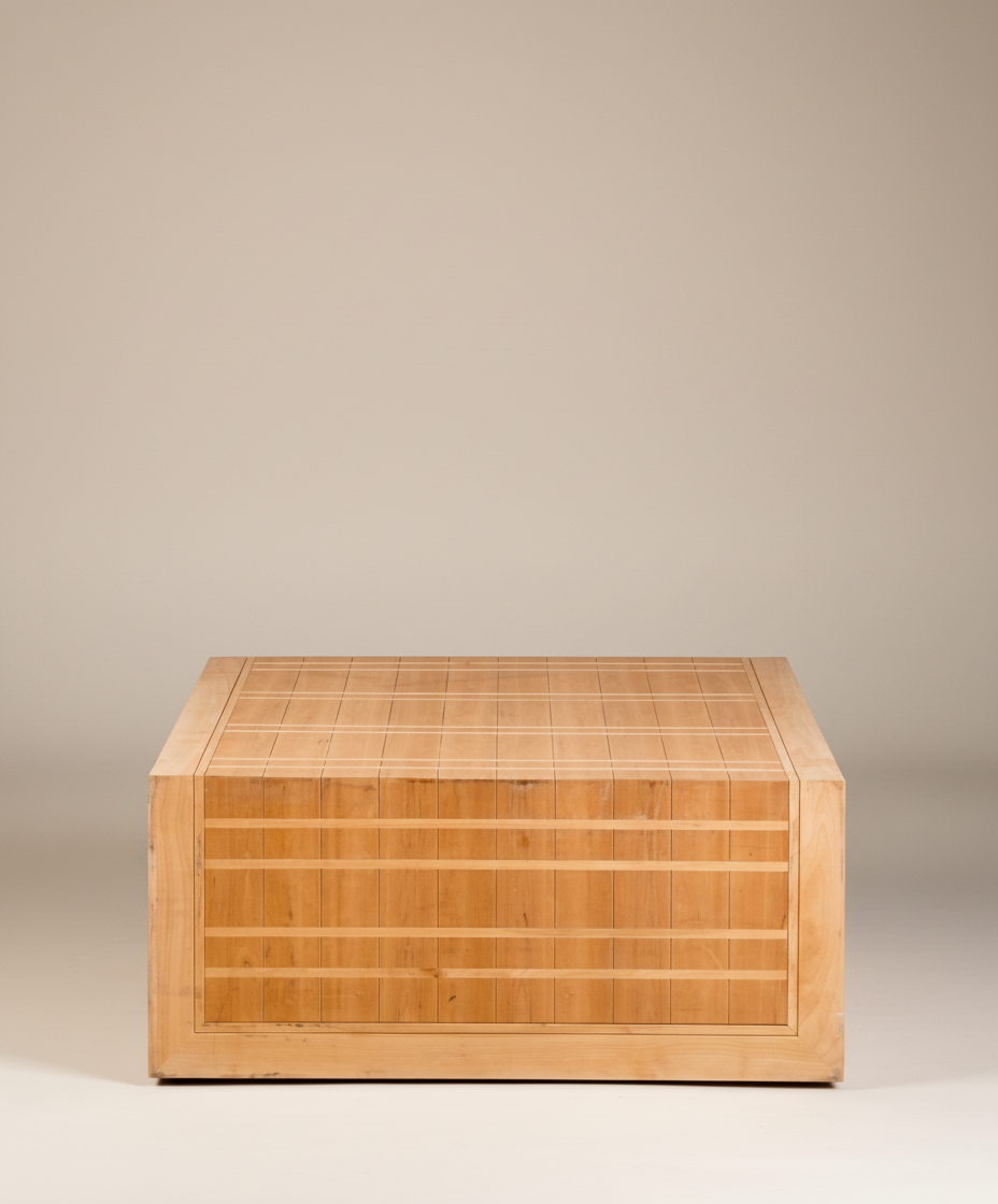  Mesa de centro cuadrada de madera clara con diseño de rejilla, vista frontal sobre fondo neutro.
