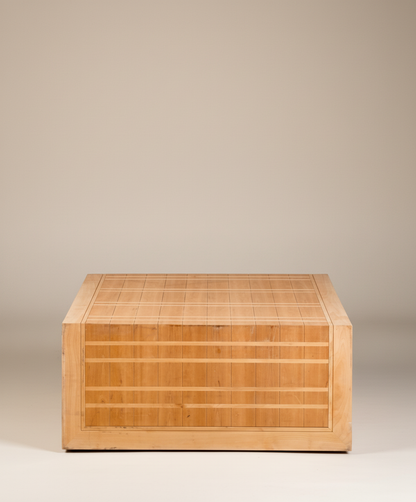  Mesa de centro cuadrada de madera clara con diseño de rejilla, vista frontal sobre fondo neutro.
