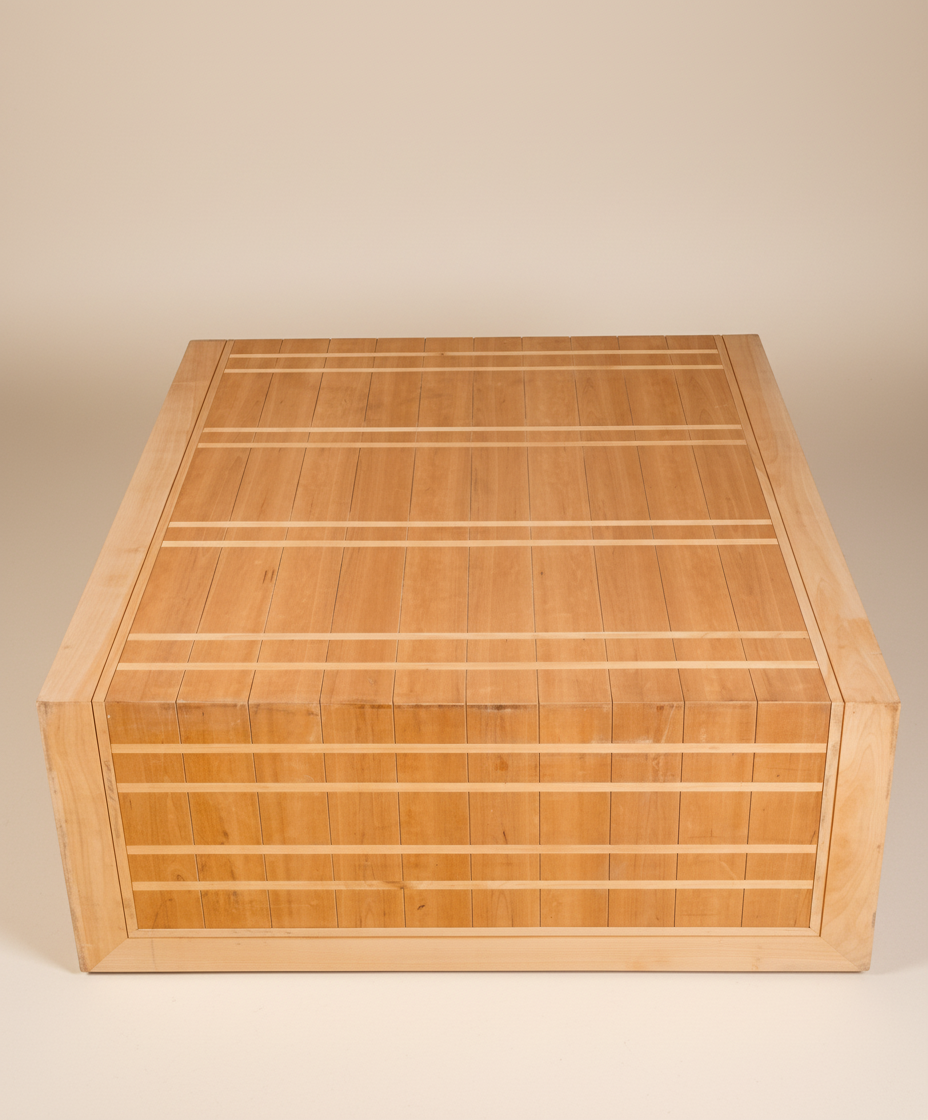 Mesa de centro artesanal de madera vista desde un ángulo superior, destacando el patrón geométrico