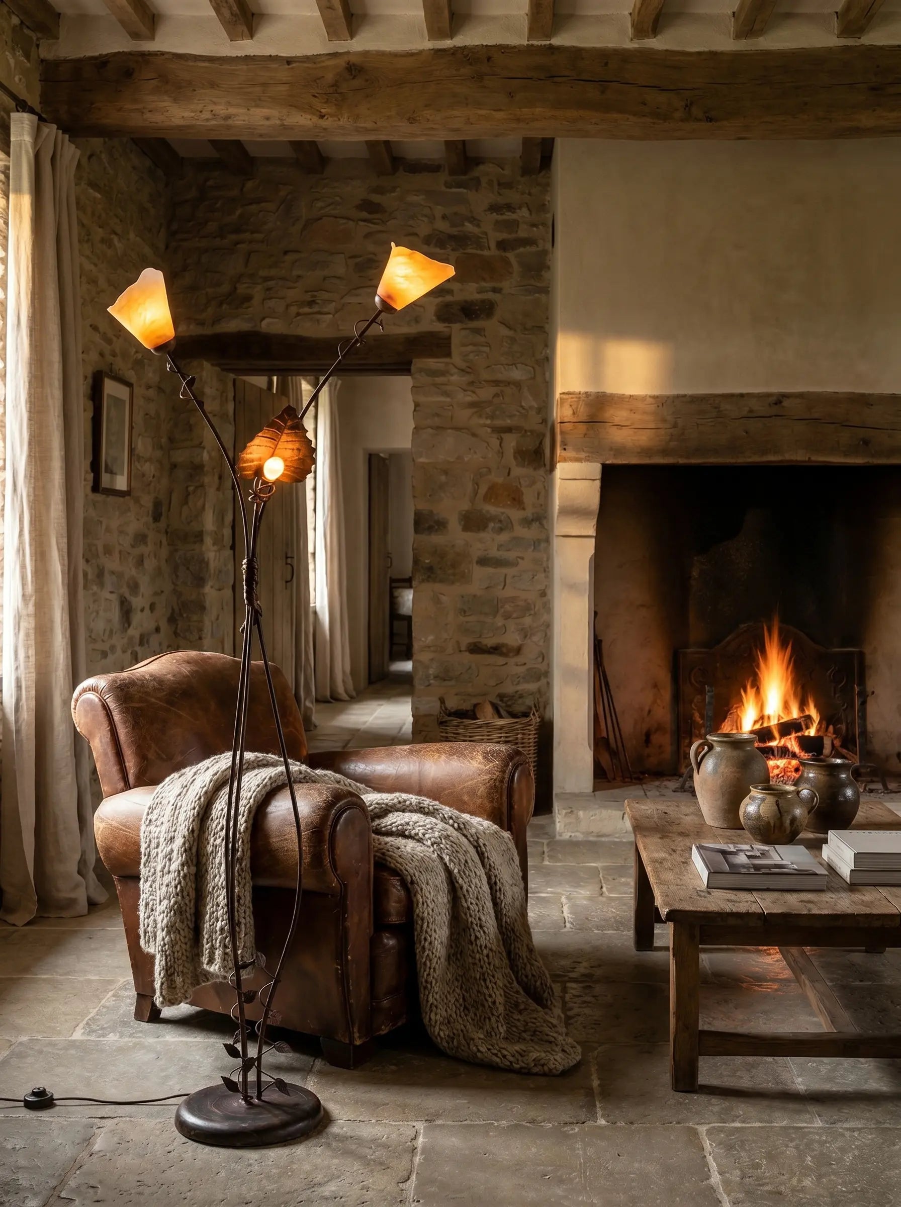 Lámpara de pie de forja encendida iluminando un salón rústico con chimenea y sillón de cuero.