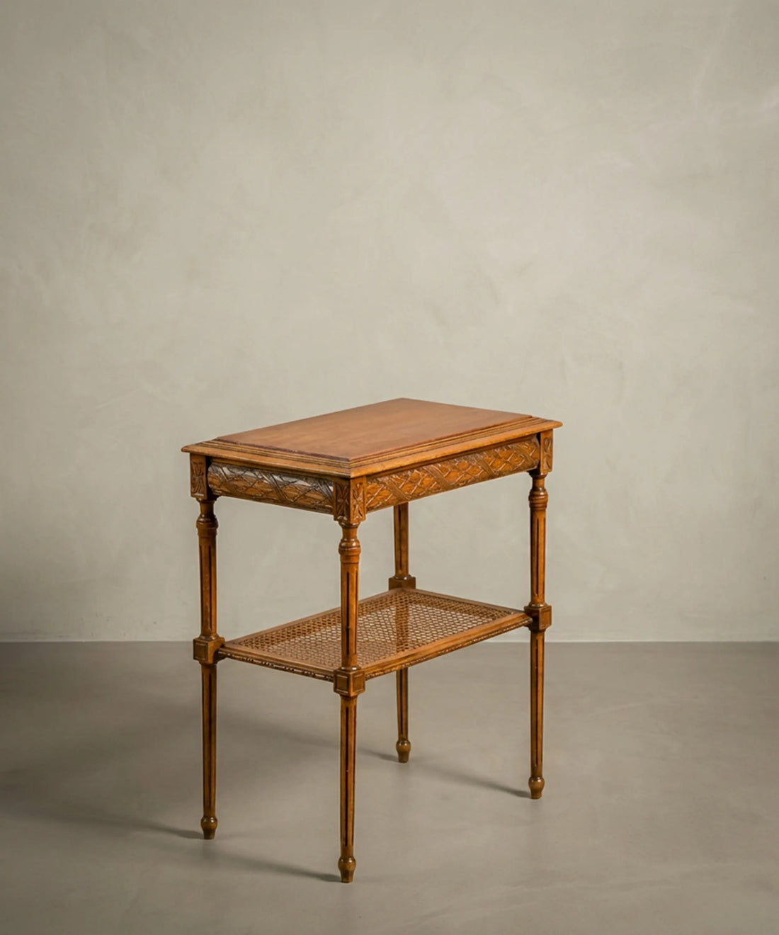 Mesa de noche vintage con diseño neoclásico y rejilla de ratán vegetal en el estante inferior.