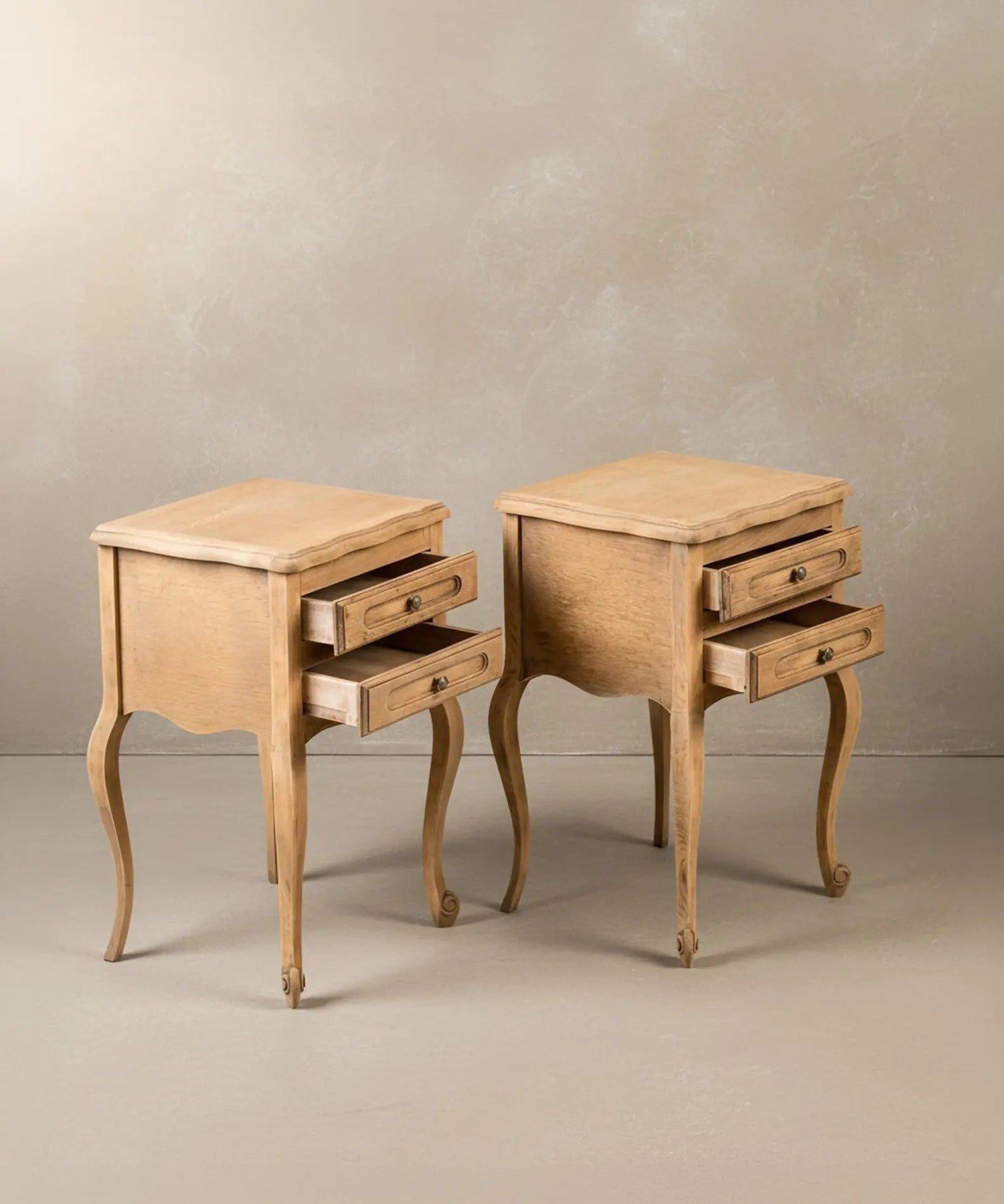 Mesita de noche estilo provenzal integrada en un dormitorio con ropa de cama de lino blanco y luz cálida.