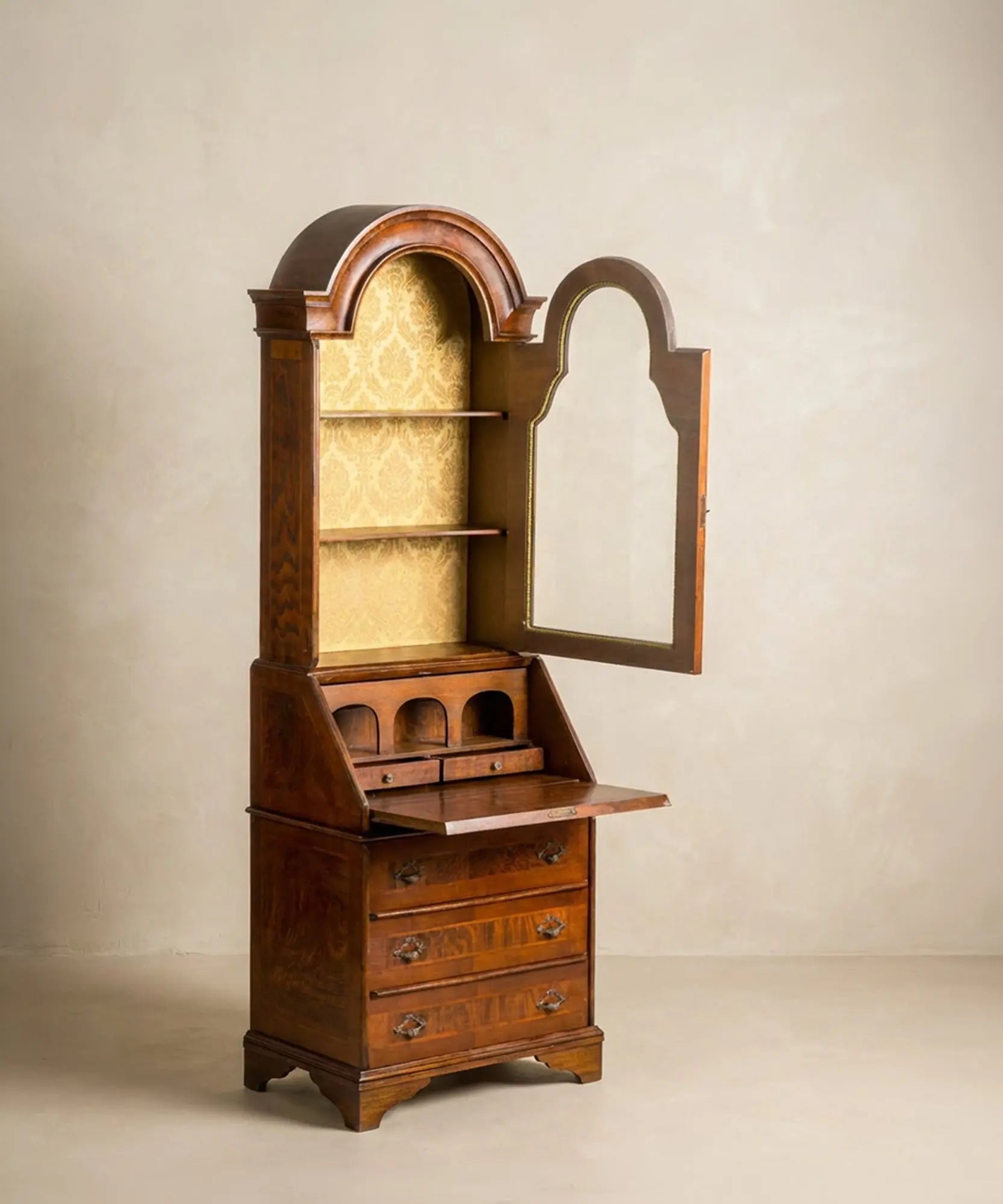 Secretaire antiguo abierto mostrando el escritorio interior con nichos, cajones pequeños y fondo de damasco dorado.