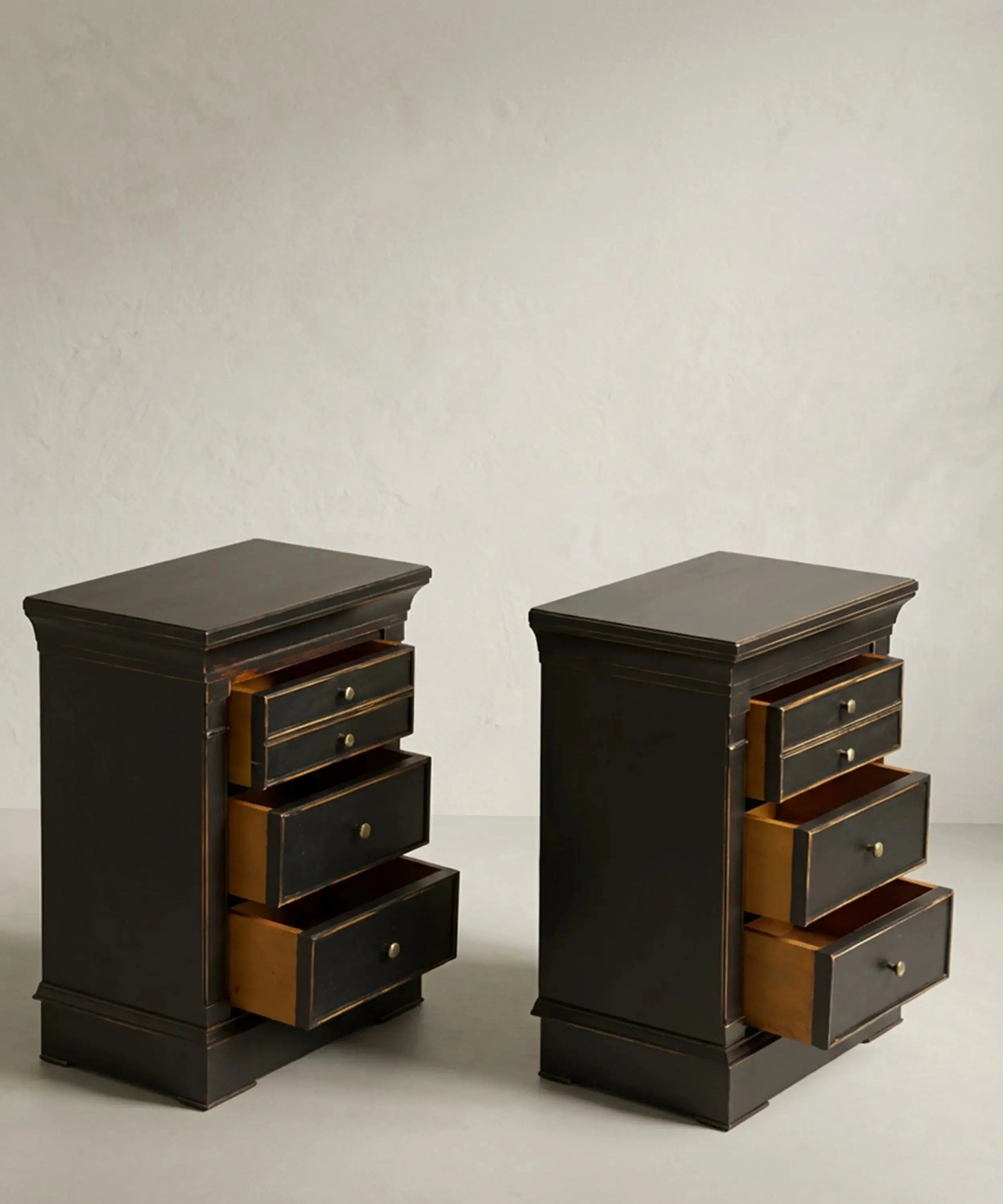 Mesitas de noche negras con los cuatro cajones de madera abiertos mostrando su capacidad.