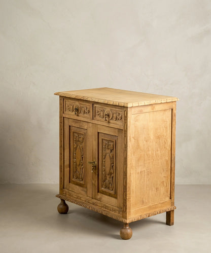 vista lateral 
Pequeño mueble aparador de madera maciza estilo renacimiento con patas de bola y puertas talladas.