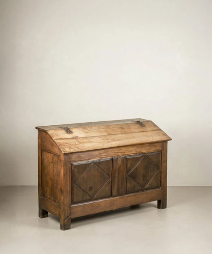 Vista frontal en ángulo de arca  antigua de madera con tapa inclinada y tallas de rombos.