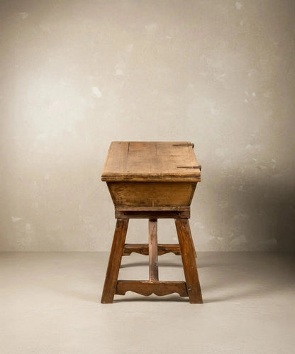 vista lateral Mesa artesa antigua de madera maciza con tapa cerrada sobre fondo neutro, estilo rústico.