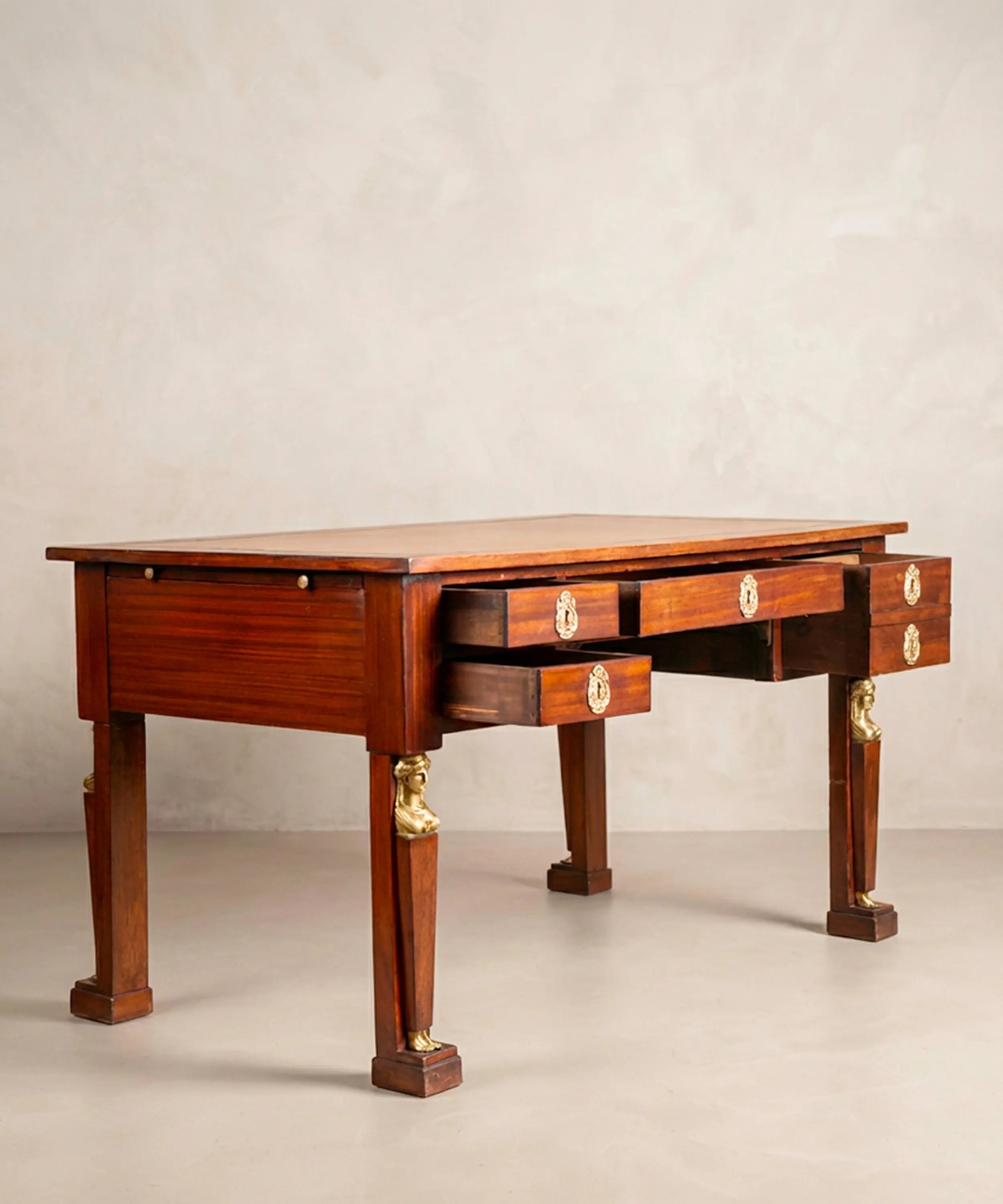 Escritorio de centro antiguo de caoba con alas laterales extraíbles abiertas y tablero de cuero cámel.