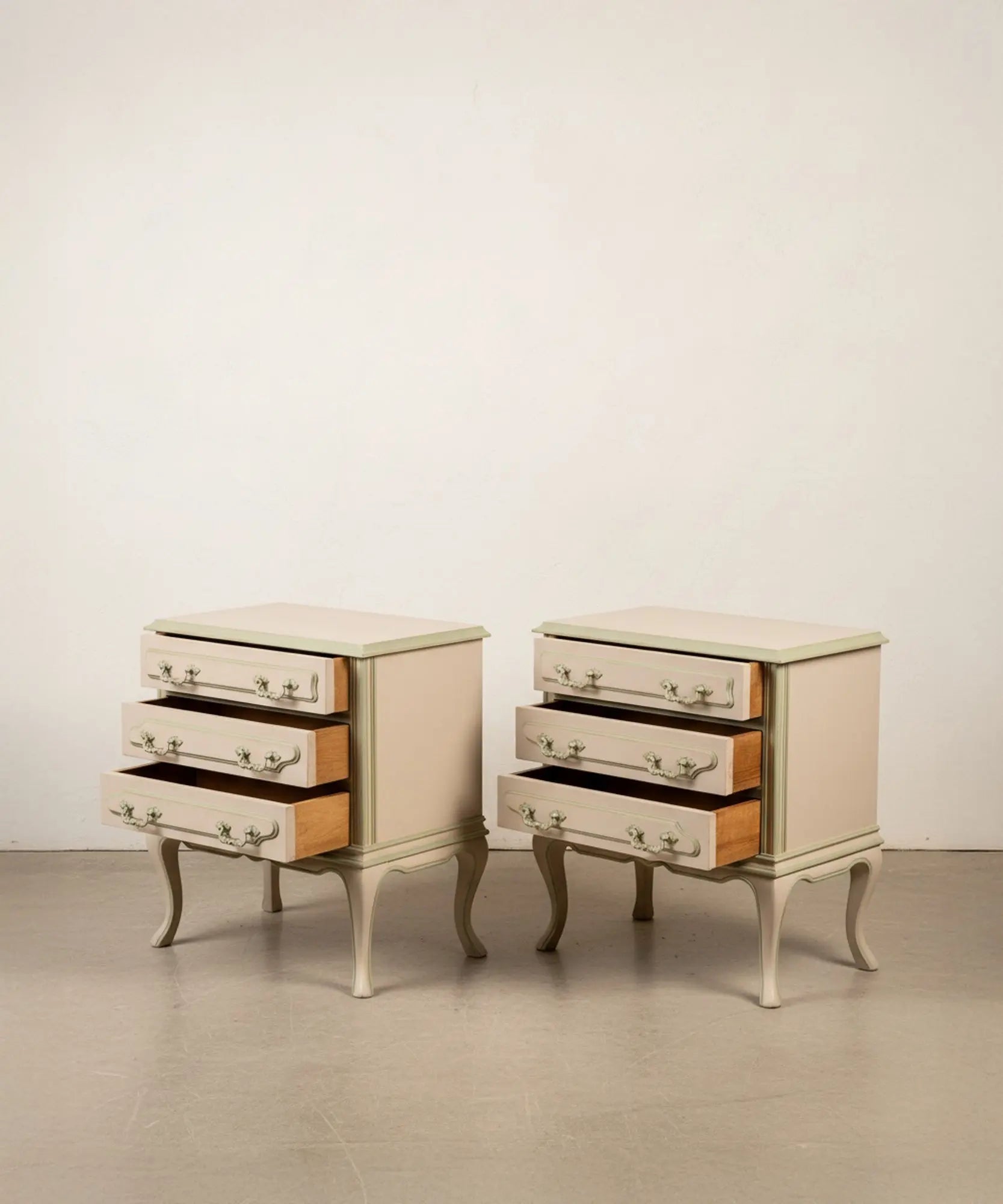 Mesitas de cama antiguas restauradas con los tres cajones abiertos mostrando el interior de madera natural.