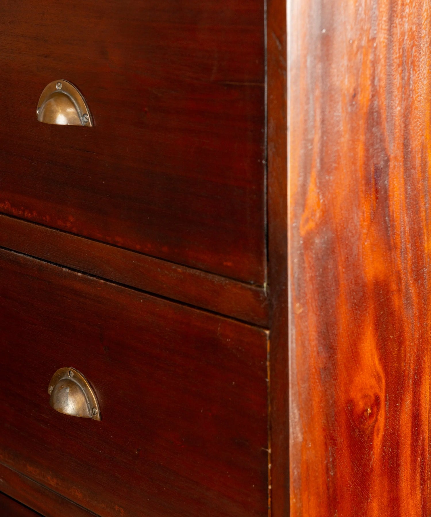 Primer plano de tiradores de concha metálicos y ensambles de cola de milano en cómoda antigua