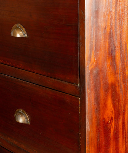 Primer plano de tiradores de concha metálicos y ensambles de cola de milano en cómoda antigua