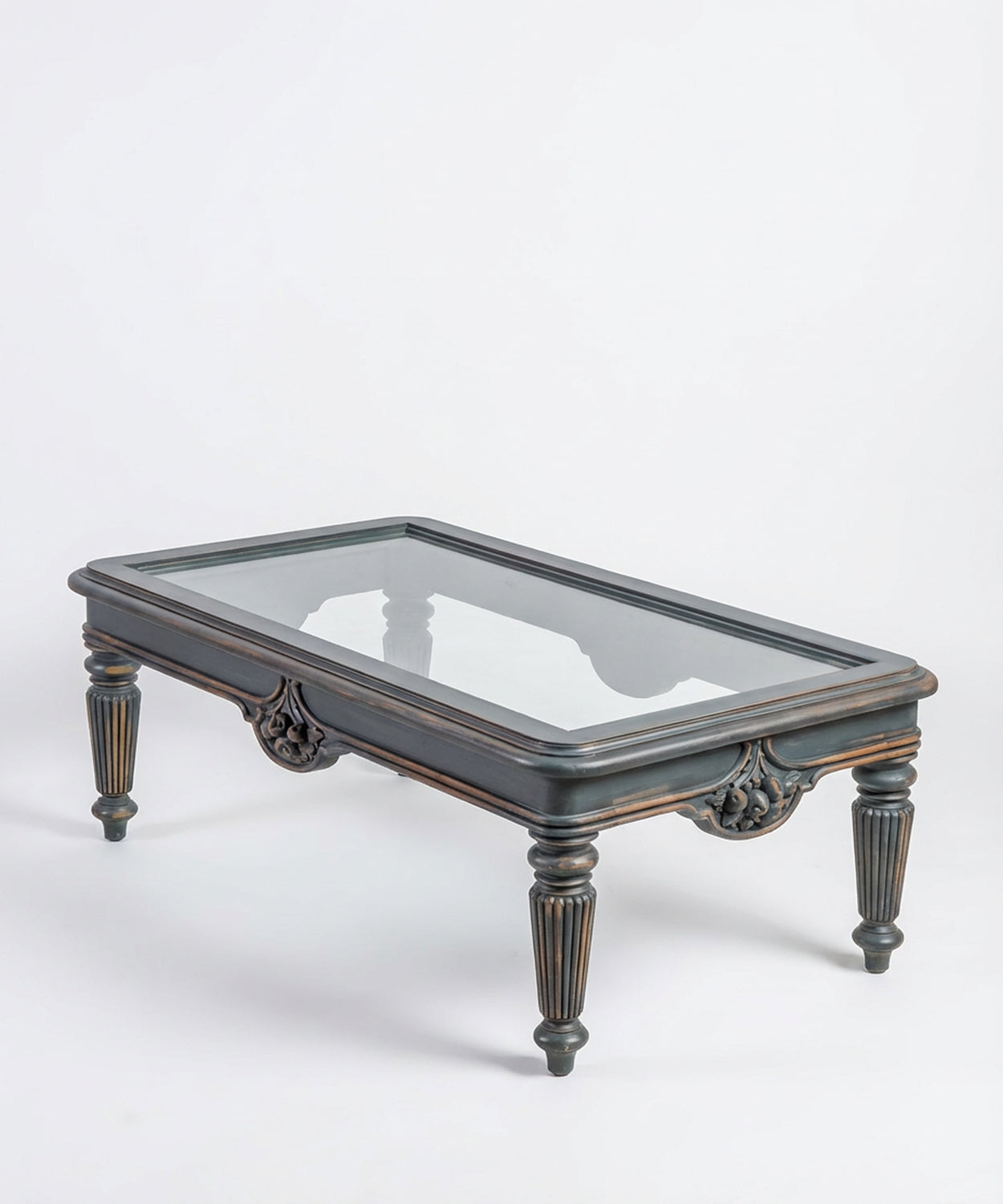 Vista en perspectiva de mesa de centro rectangular gris con cristal y patas talladas