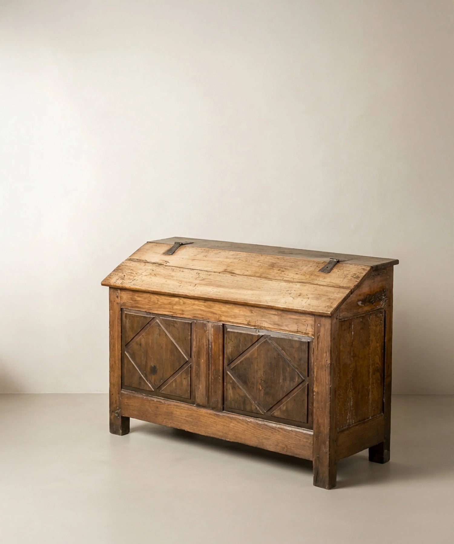 Vista  en ángulo de arca  antigua de madera con tapa inclinada y tallas de rombos.