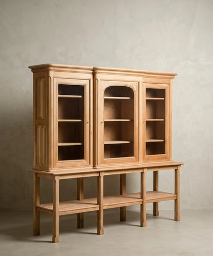 Vista frontal de alacena de tres cuerpos en madera clara natural sobre fondo de pared texturizada gris.