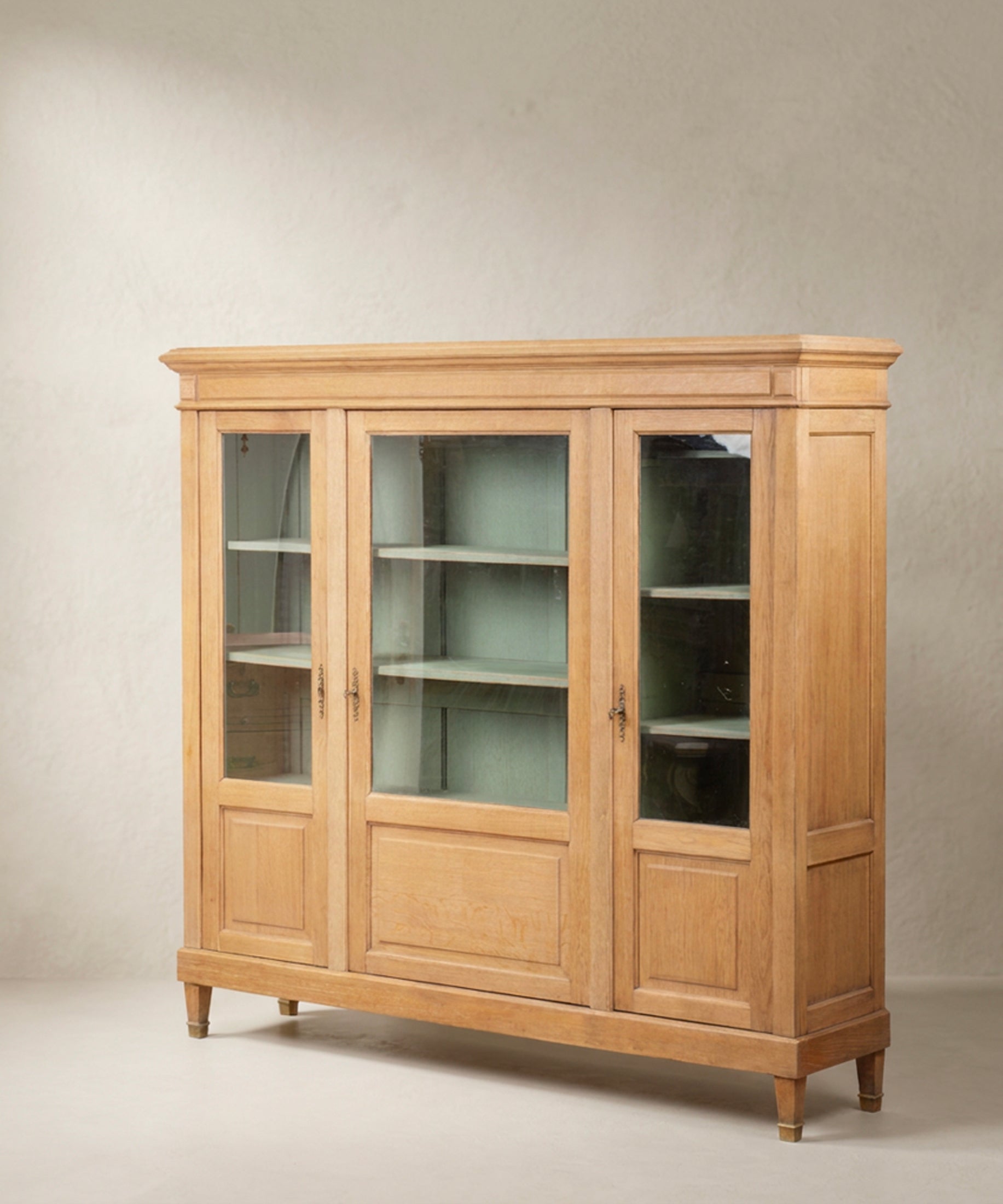 Vitrina de roble vista lateral con costado panelado y zapatas de latón — Antique Arte y Decoración