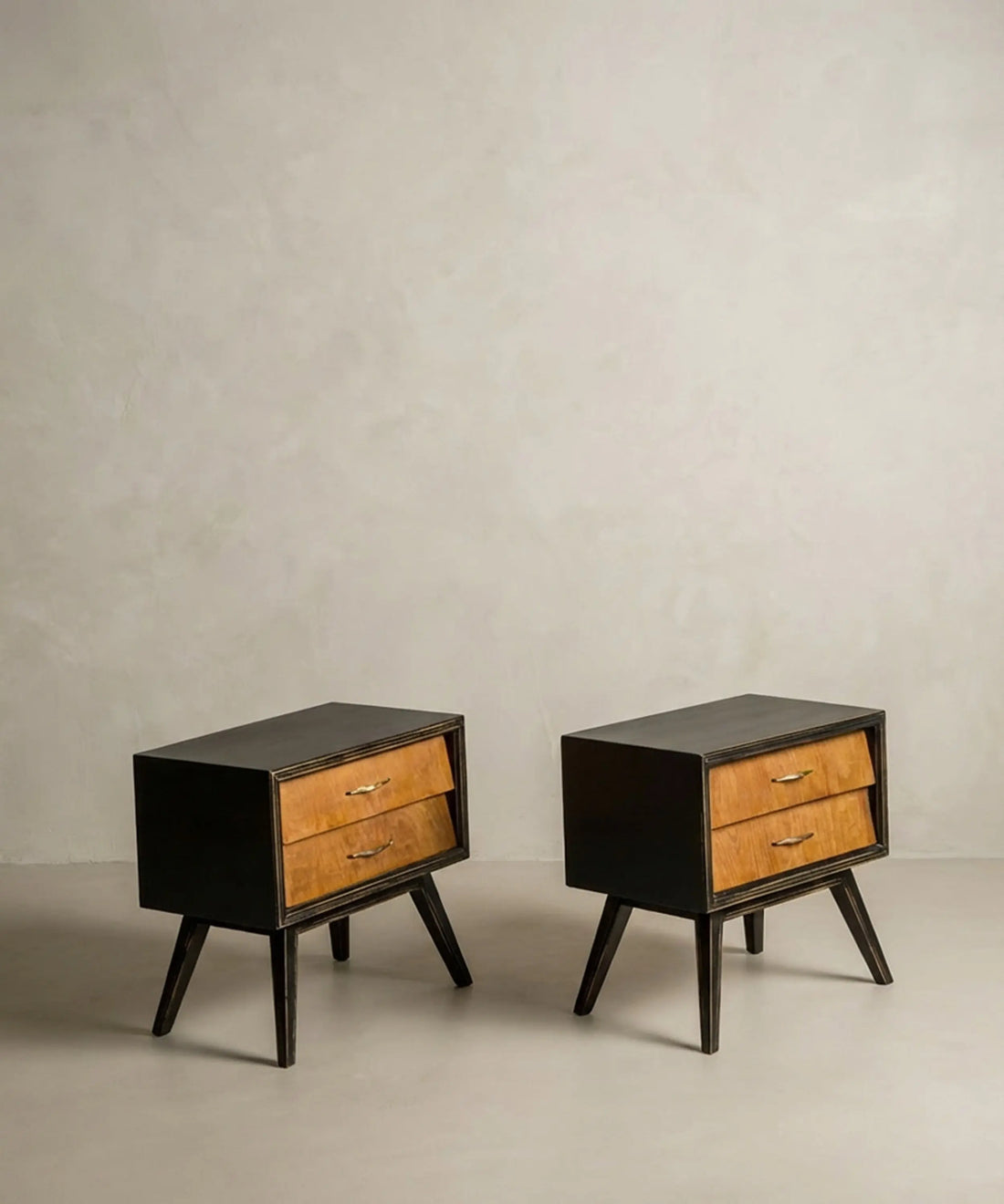 Vista lateral de mesita años 50 con patas de compás y cajones inclinados en madera.