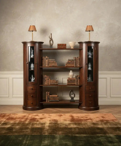 Librería completa estilo colonial con libros y decoración, iluminada con lámparas clásicas sobre torres cilíndricas.