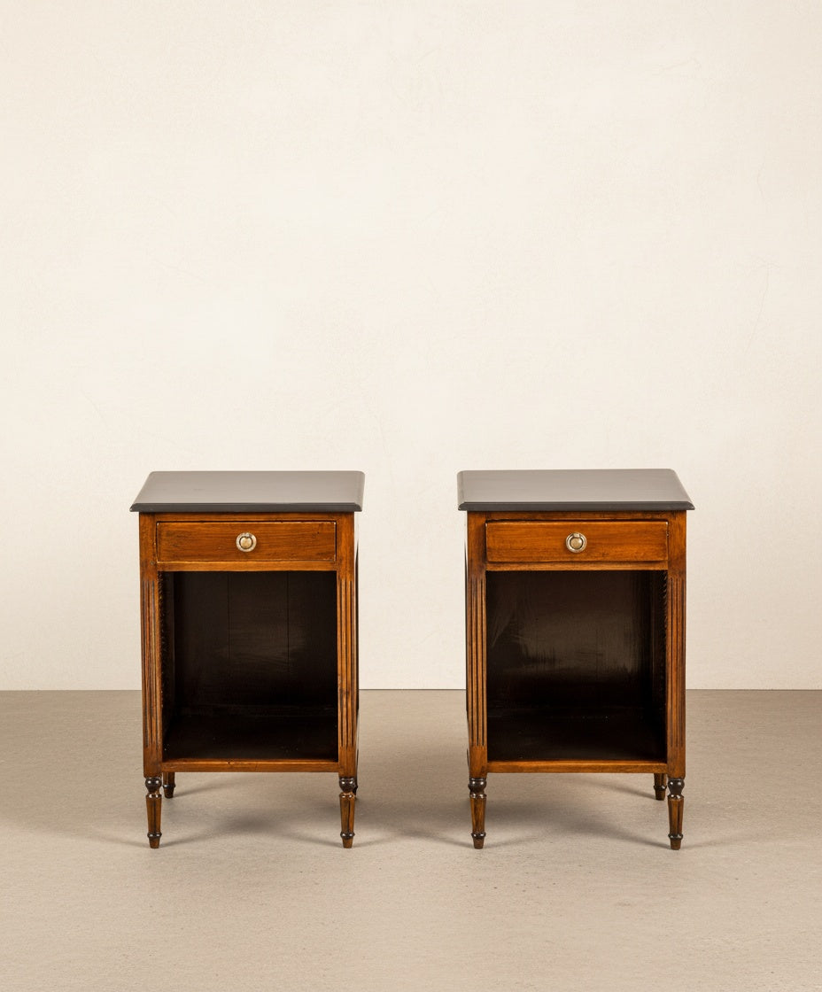 Pareja de mesitas de noche neoclásicas en madera con cajón y estante inferior, fondo neutro.
