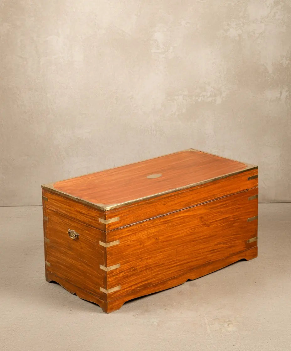  Baúl de campaña británico en madera de caoba cerrada, vista frontal mostrando herrajes de latón y veta natural.