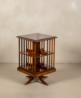 Mesa de biblioteca giratoria de madera clásica con dos estantes y listones verticales sobre fondo neutro.