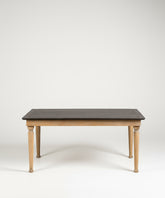 Mesa de comedor rectangular de estilo rústico con patas de madera natural y superficie oscura, fotografiada de frente en un estudio con fondo blanco.