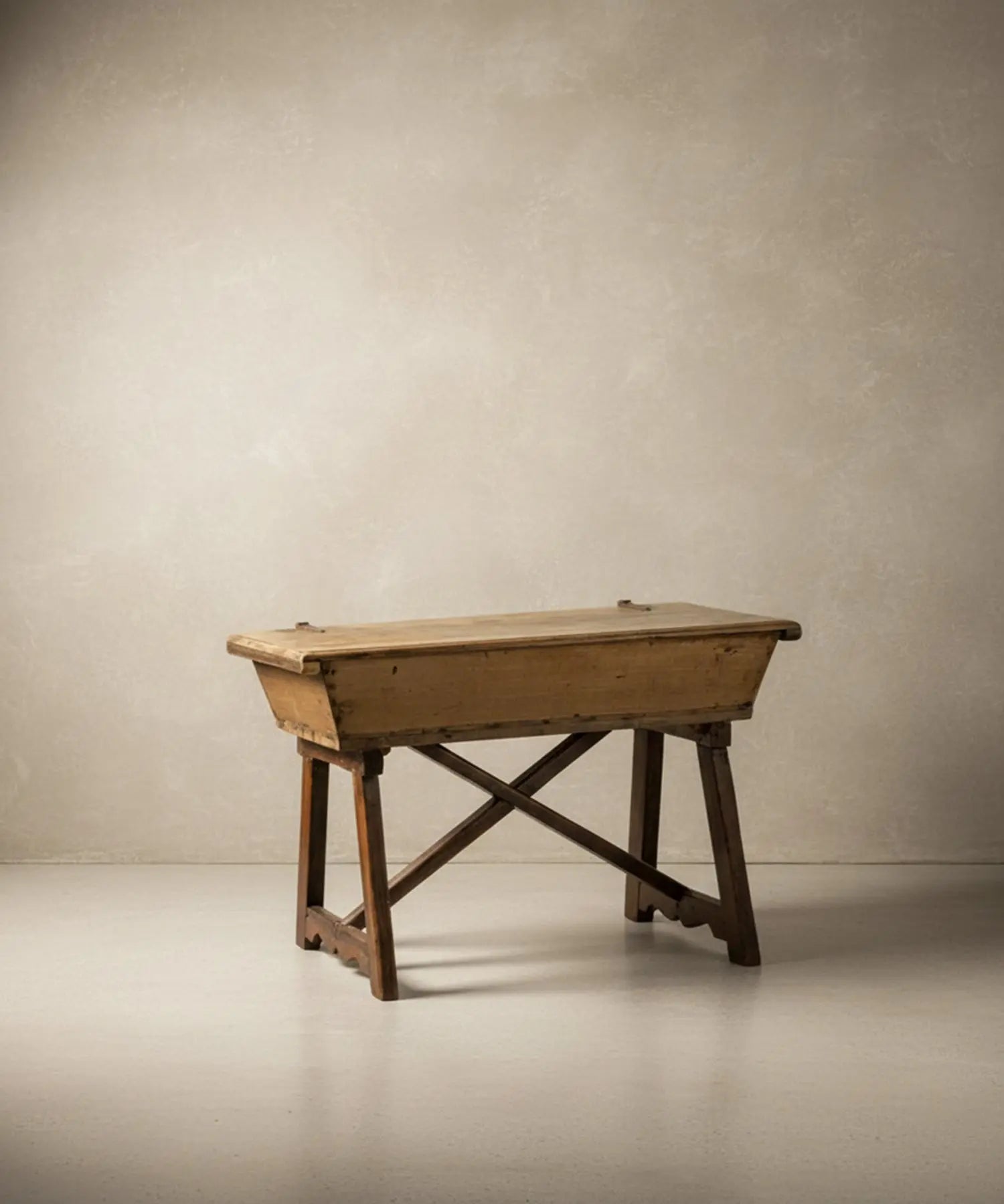 Mesa artesa antigua de madera maciza con tapa cerrada sobre fondo neutro, estilo rústico.