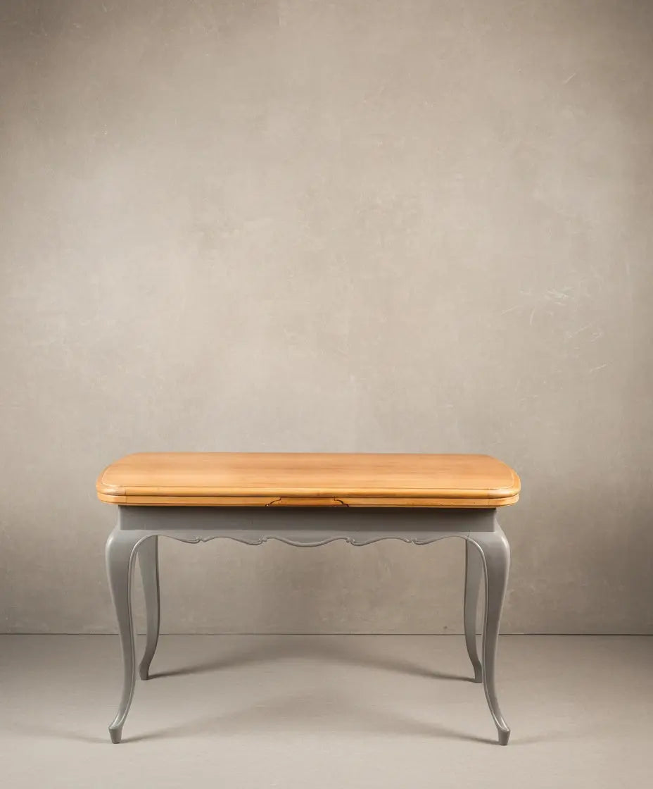 Mesa extensible clásica renovada cerrada, mostrando frente ondulado pintado en gris y tapa de madera.