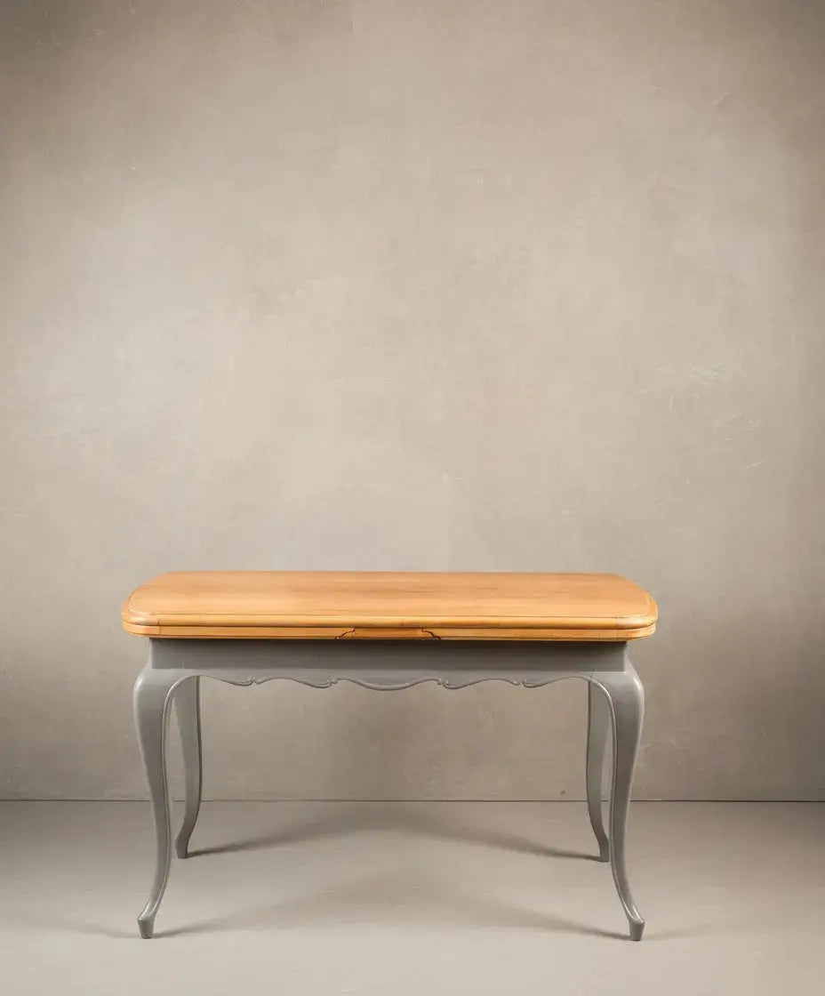 Mesa extensible clásica renovada cerrada, mostrando frente ondulado pintado en gris y tapa de madera.