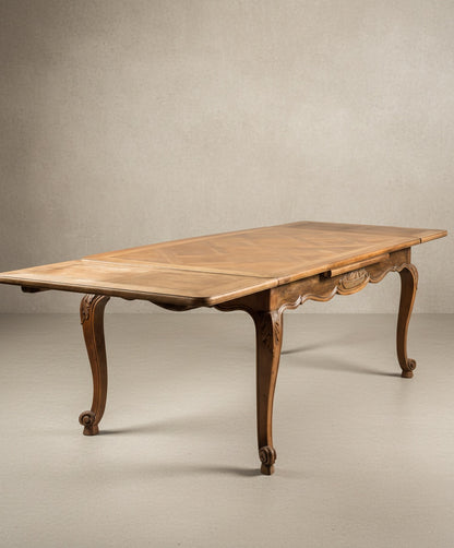 Mesa de comedor Luis XV con alas extensibles abiertas mostrando la versatilidad del tablero.