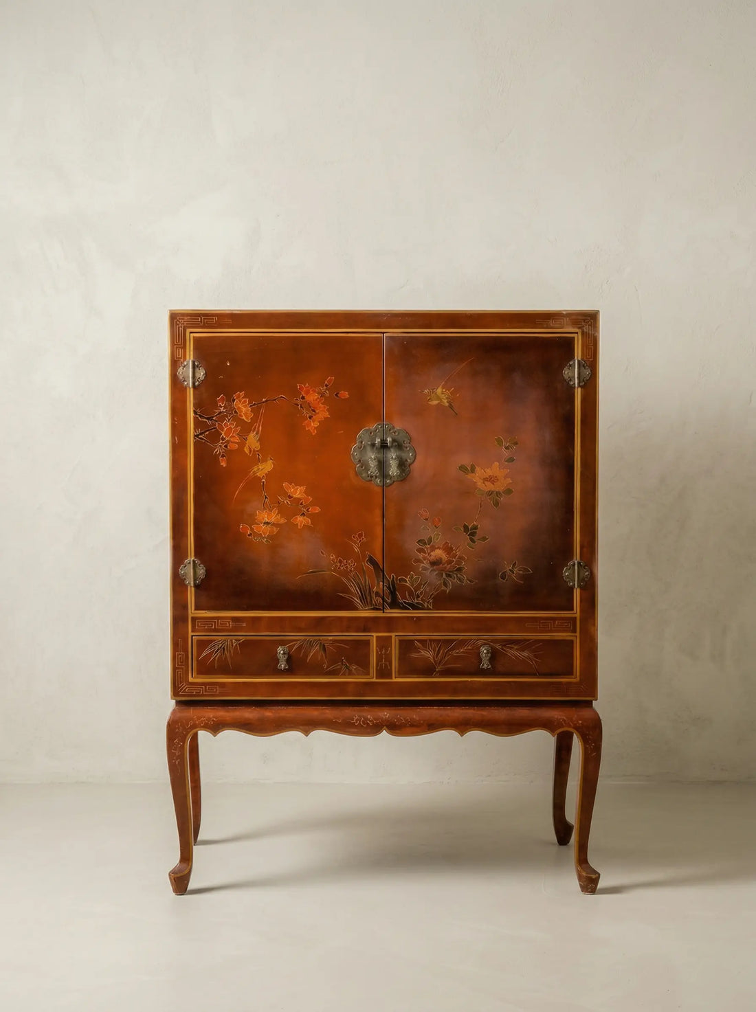 Gabinete chinoiserie de laca ámbar con pintura de aves y flores sobre fondo neutro.