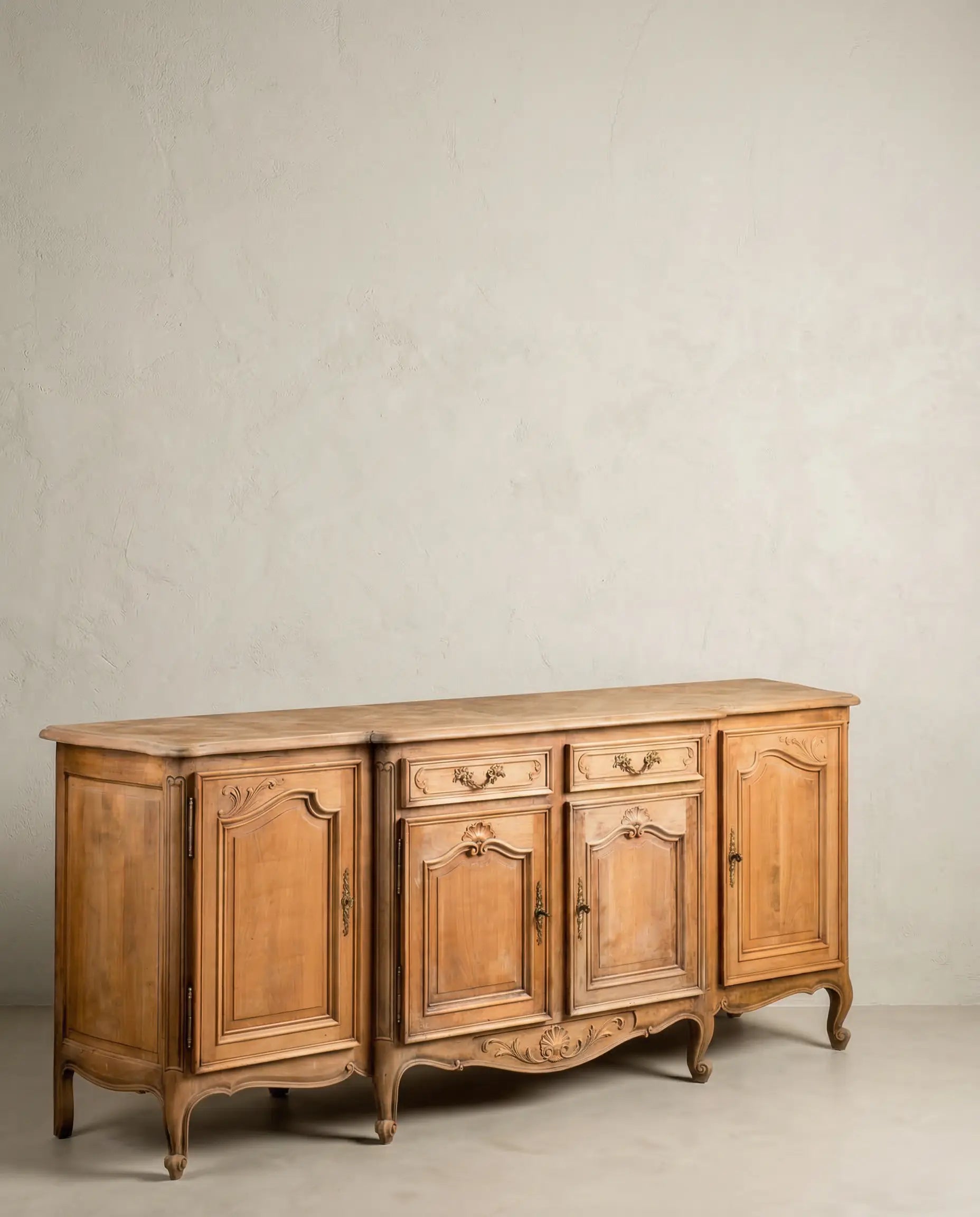 Mueble aparador estilo Luis XV en madera clara con detalles tallados y tapa geométrica.