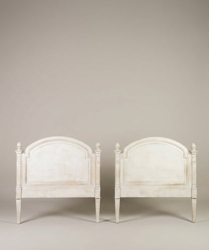 Pareja de cabeceros blancos estilo provenzal alineados sobre fondo neutro