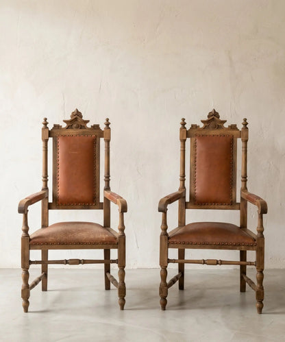 Pareja de sillones fraileros clásicos de madera y cuero marrón con tachuelas.