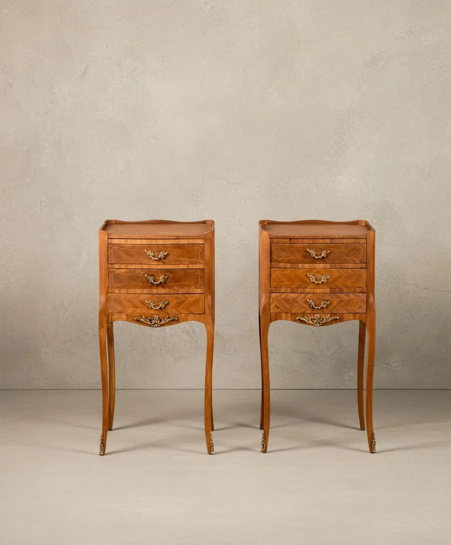 Vista frontal de pareja de mesitas de noche francesas estilo Luis XV en madera con tres cajones y patas altas.