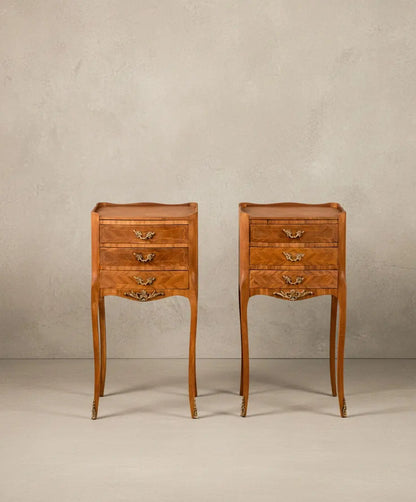 Vista frontal de pareja de mesitas de noche francesas estilo Luis XV en madera con tres cajones y patas altas.