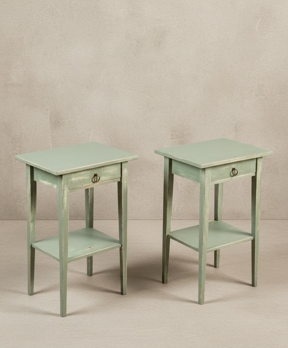 Vista en ángulo de las mesitas de noche verdes mostrando la textura del acabado decapé y el diseño de las patas.
