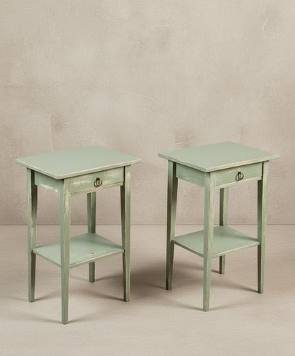 Vista en ángulo de las mesitas de noche verdes mostrando la textura del acabado decapé y el diseño de las patas.