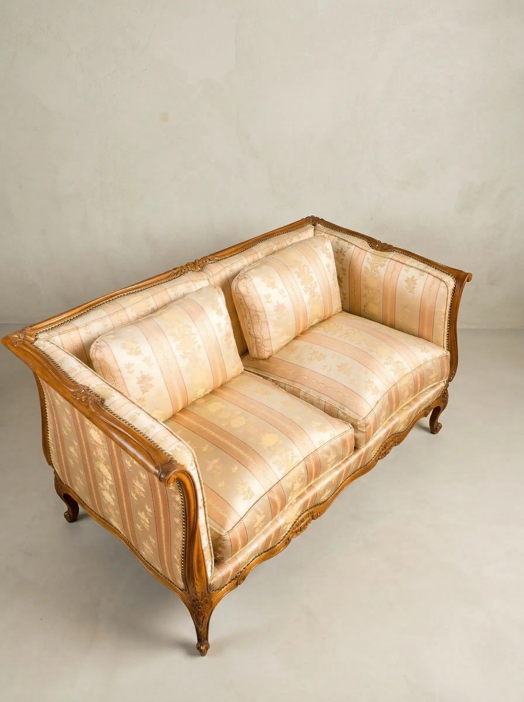 Vista superior de tapicería floral a rayas en tonos crema y melocotón de un sofá vintage.