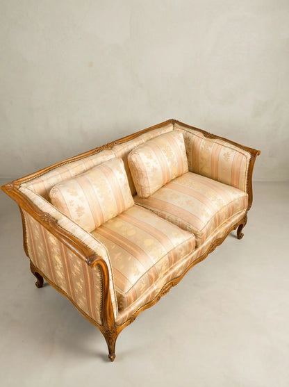 Vista superior de tapicería floral a rayas en tonos crema y melocotón de un sofá vintage.