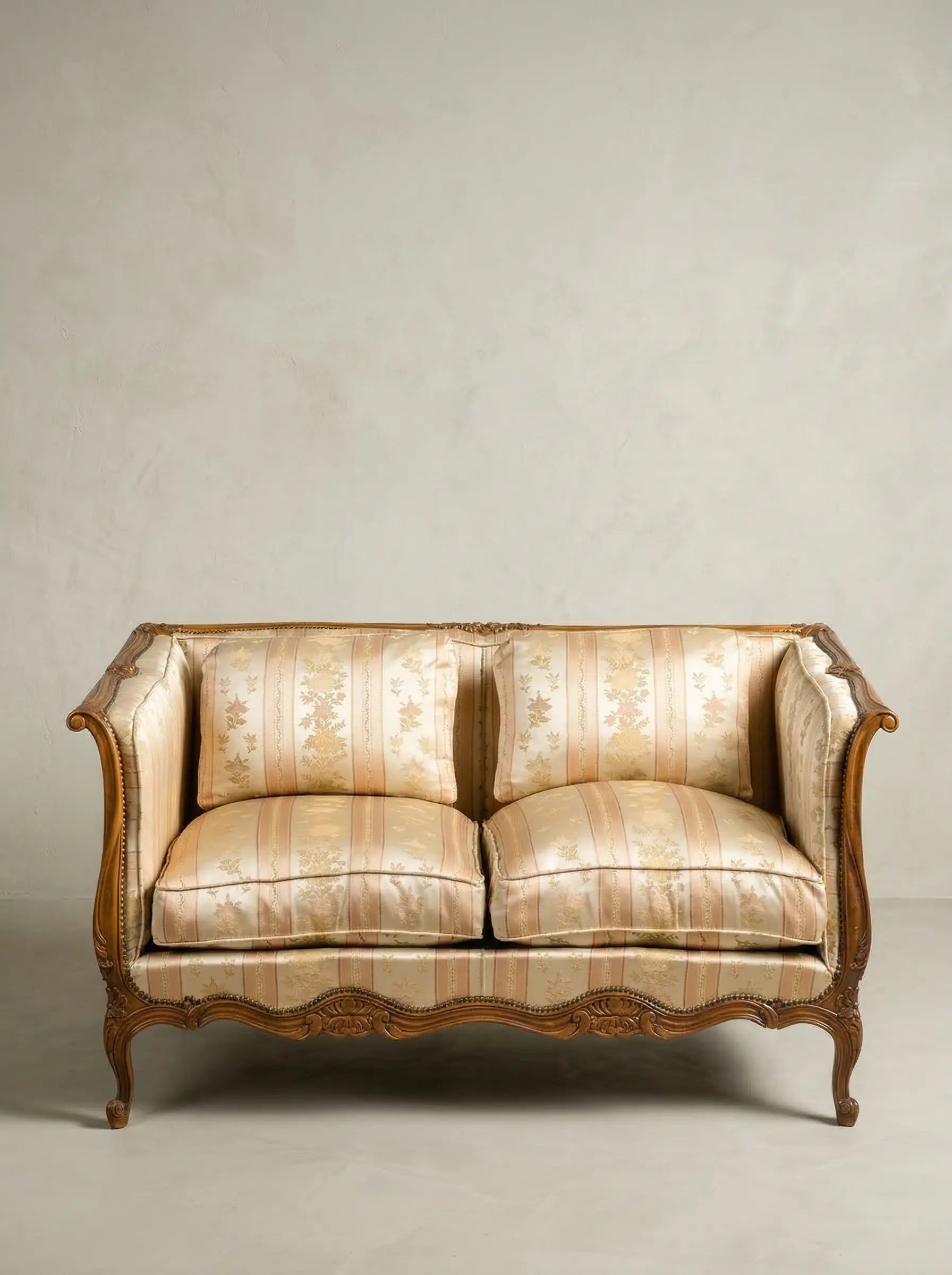 Sofá canapé vintage de dos plazas estilo Luis XV con tapicería de damasco frente a pared neutra.