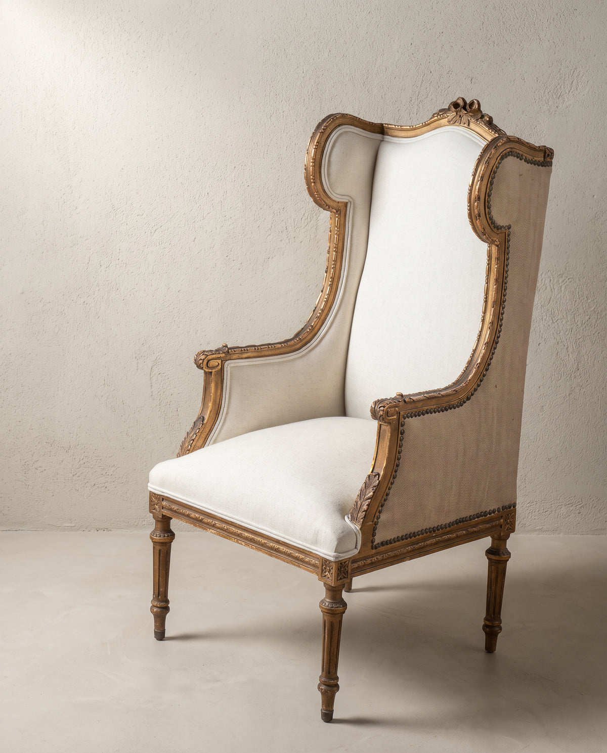 Sillón orejero antiguo francés vista de tres cuartos, lazo tallado en el copete — Antique Arte y Decoración