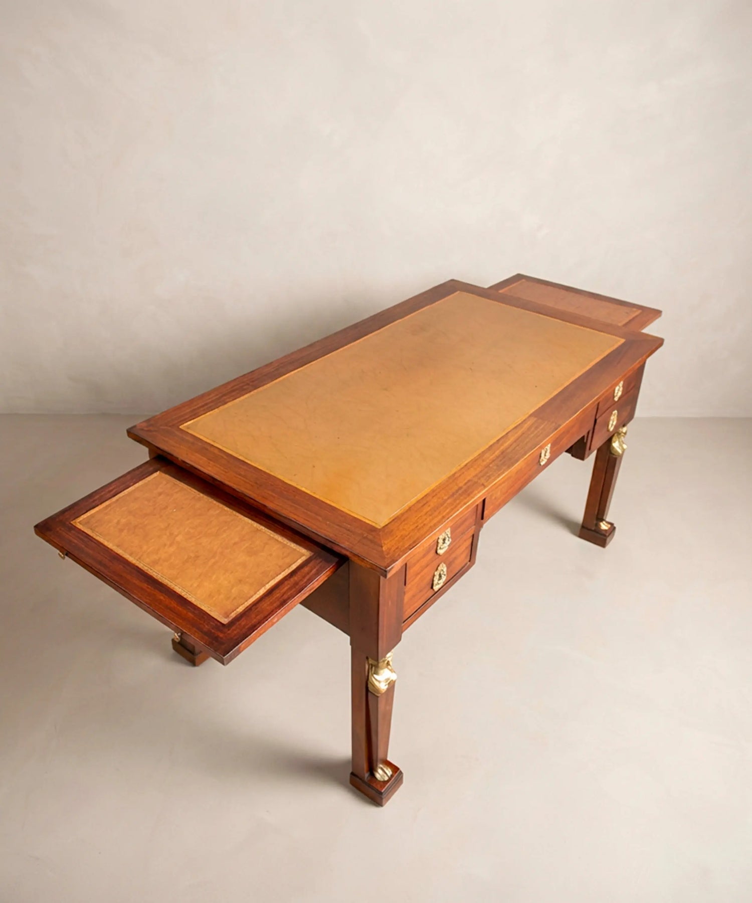Escritorio de centro antiguo de caoba con alas laterales extraíbles abiertas y tablero de cuero cámel.
