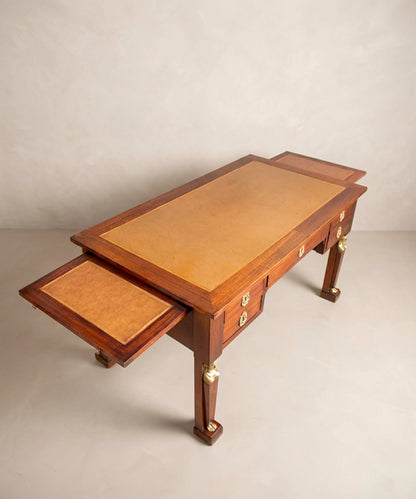 Escritorio de centro antiguo de caoba con alas laterales extraíbles abiertas y tablero de cuero cámel.