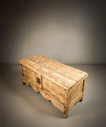 Vista lsuperior de baúl antiguo de madera clara resaltando la veta natural y estructura robusta.