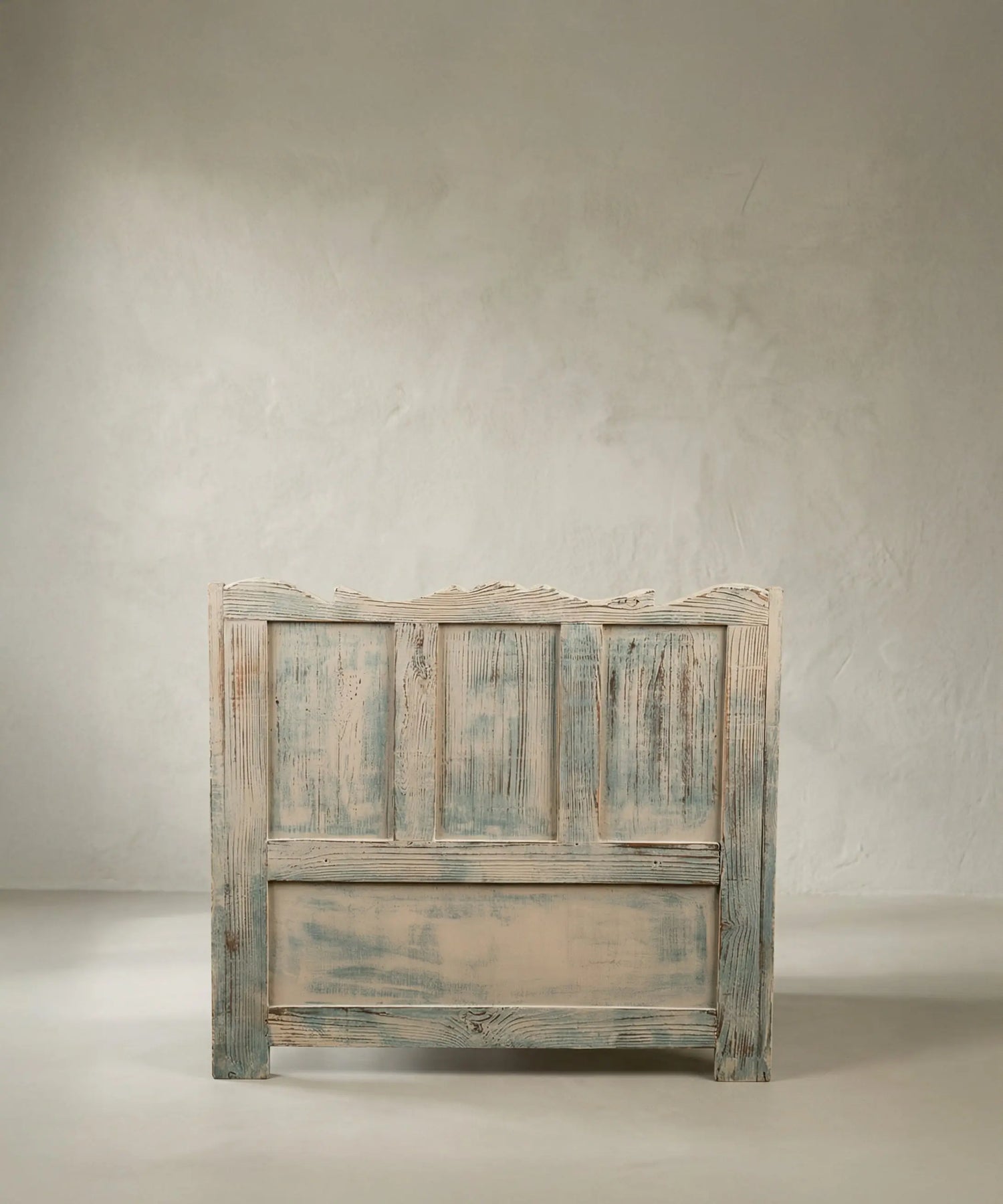 Parte trasera de banco rústico de madera panelada con acabado de pintura desgastada.