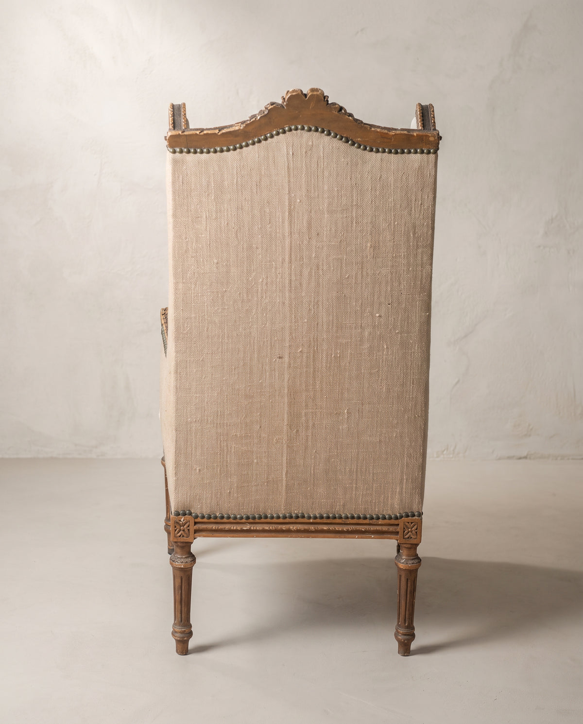 Sillón orejero Luis XVI vista trasera en arpillera con tachuelas y rosetas talladas — Antique Arte y Decoración