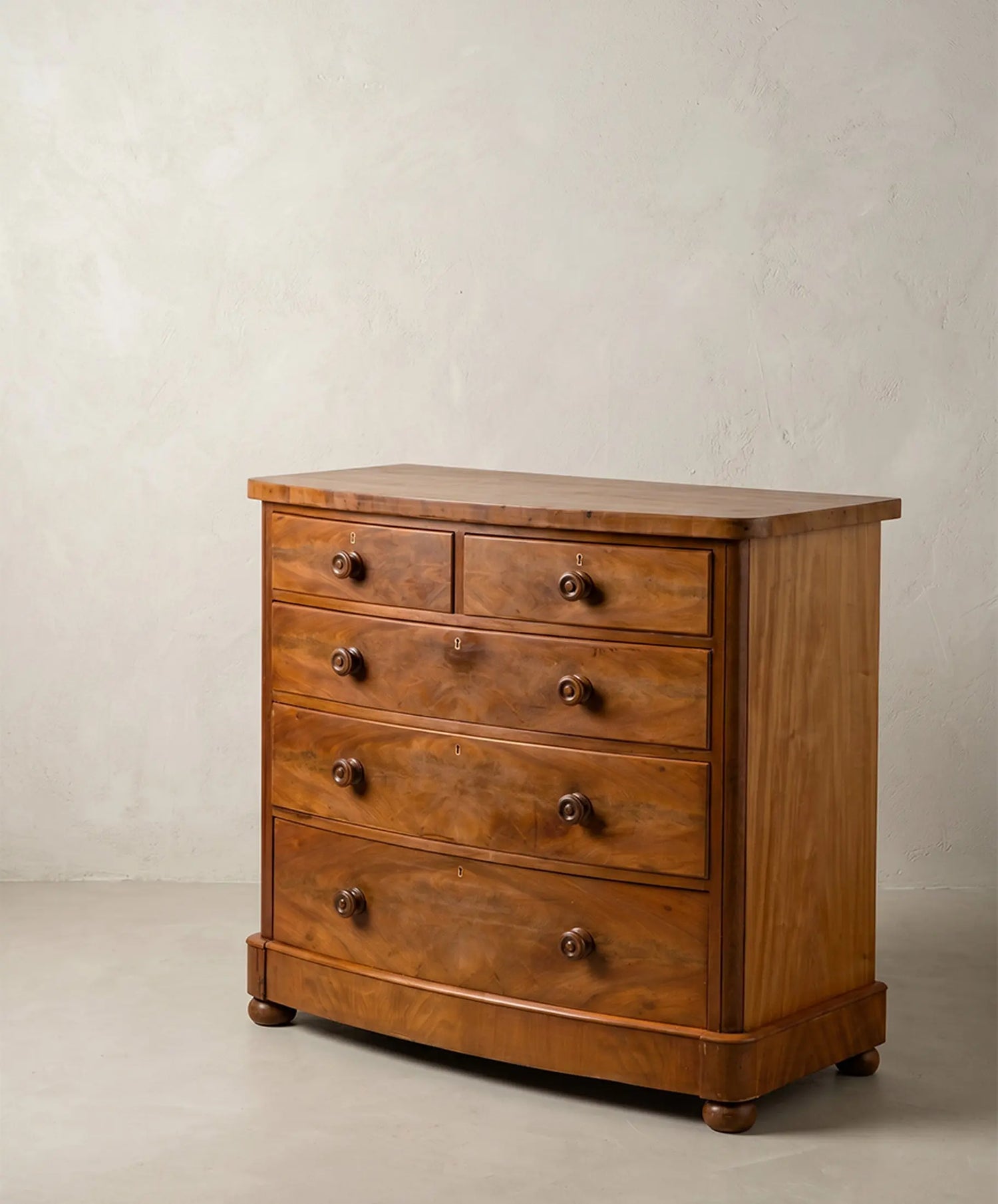 Cómoda Inglesa antigua de frente curvo en madera de pluma de caoba (S. XIX)